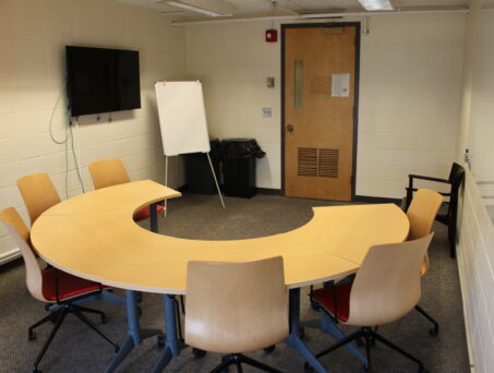 Semi circle table with chairs and TV. Click on this picture to reserve this room.