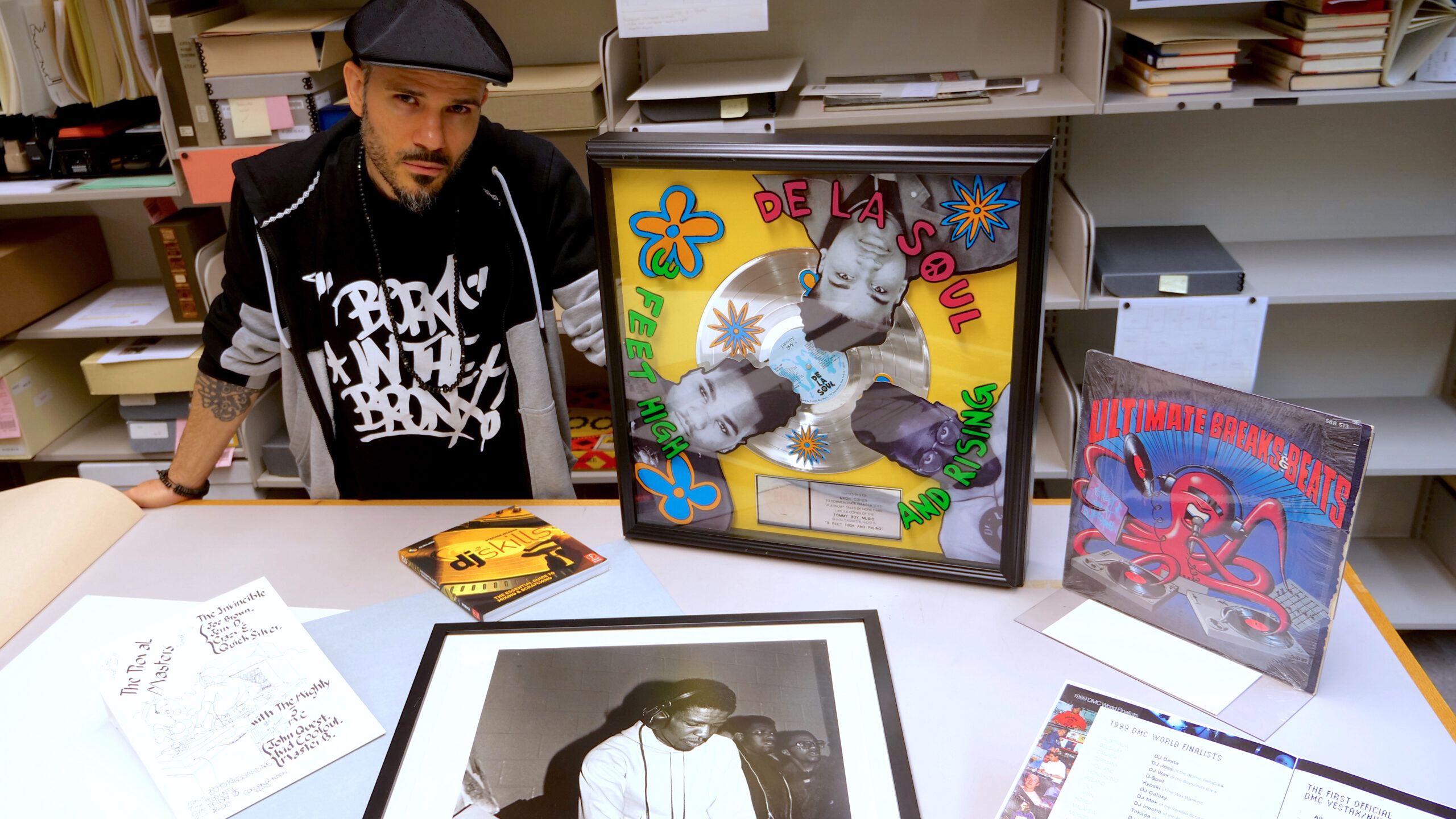 Ben Ortiz stands next to a table where different hip-hop artifacts are strewn.