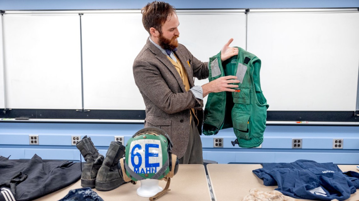 Christopher Mahn ’24 holds up a float coat he wore as a mechanic on an aircraft carrier. 
